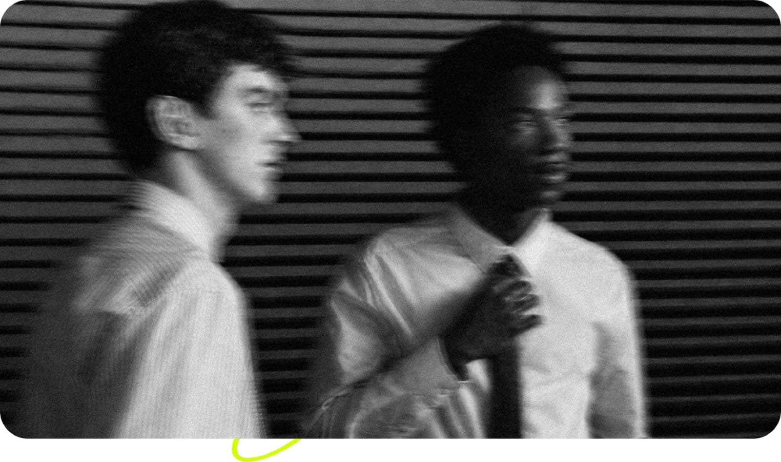 Two people walking fast past a steel shutter, blurred with motion